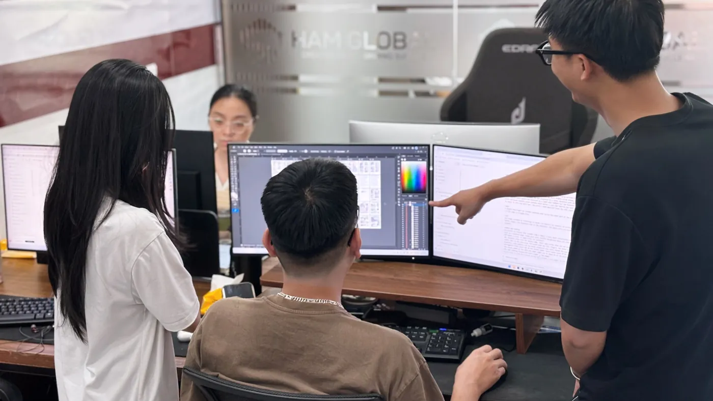 Two team members reviewing a design on a monitor while a colleague points at the screen